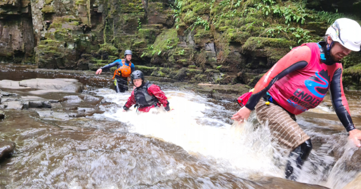 group of people walking through river as they gorge walk in the Durham Dales